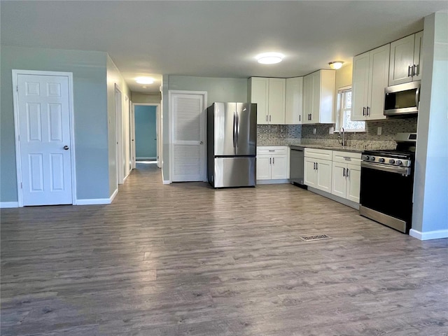 kitchen featuring decorative backsplash, white cabinets, stainless steel appliances, and a sink