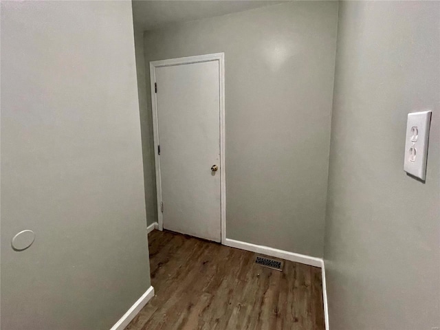 hallway with visible vents, wood finished floors, and baseboards