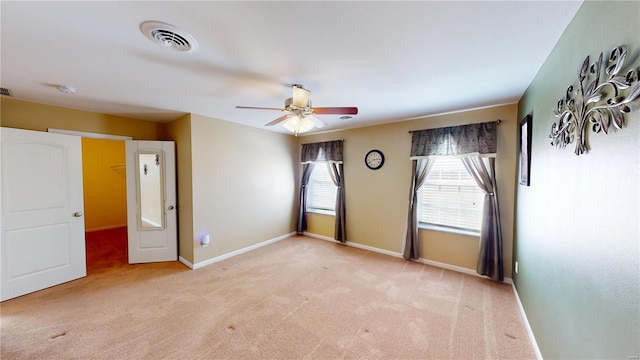 carpeted empty room with visible vents, baseboards, and ceiling fan