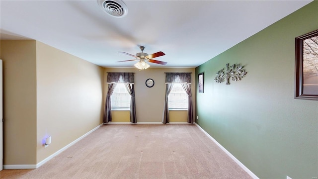 unfurnished room with visible vents, light colored carpet, baseboards, and ceiling fan