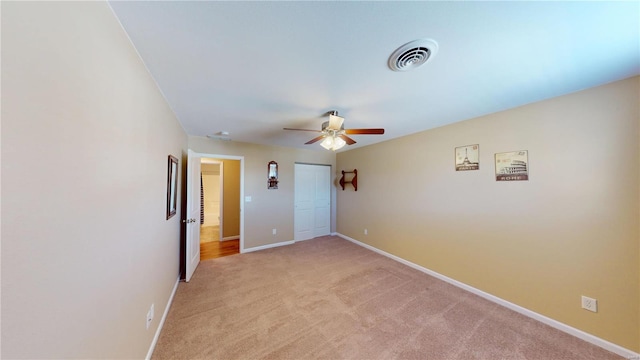 spare room featuring a ceiling fan, light colored carpet, visible vents, and baseboards