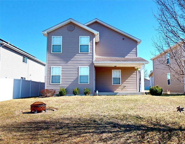 back of property with a lawn, an outdoor fire pit, and fence