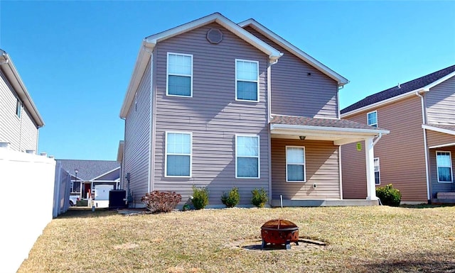 rear view of property featuring central AC unit, a yard, and a fire pit