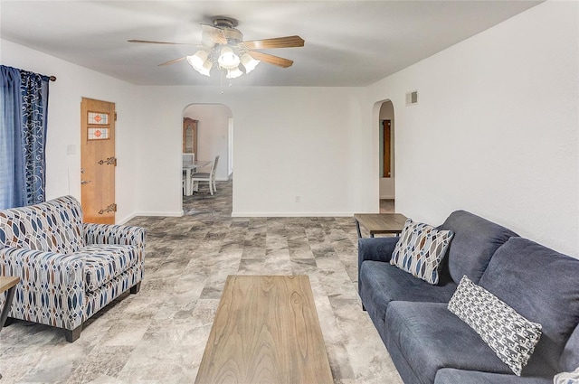 living area featuring arched walkways, visible vents, baseboards, and ceiling fan