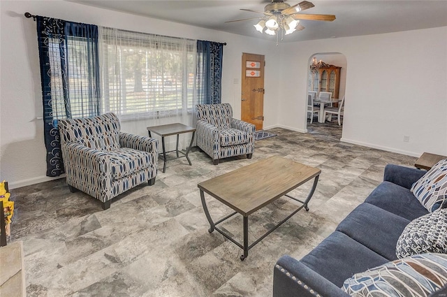 living room with baseboards, arched walkways, and ceiling fan