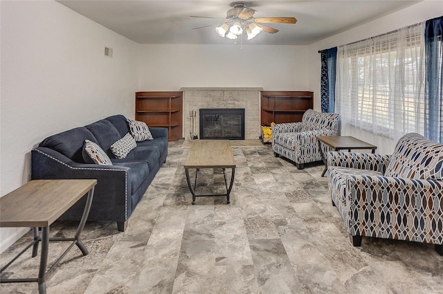 living room featuring visible vents, a glass covered fireplace, and a ceiling fan