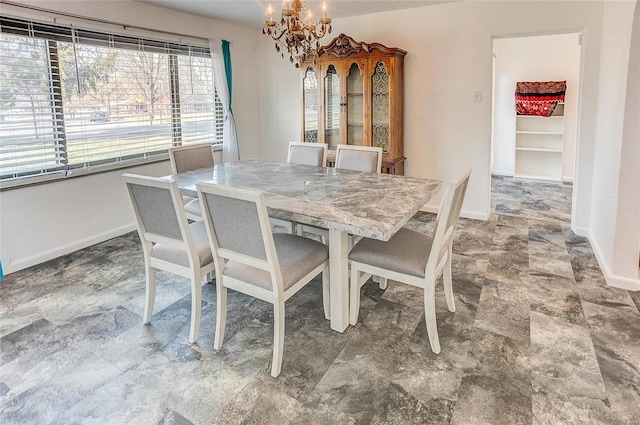 dining area featuring a chandelier, stone finish floor, and baseboards