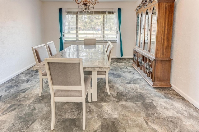 dining space with stone finish flooring, plenty of natural light, baseboards, and a chandelier