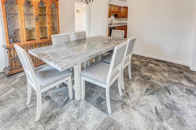 dining space with baseboards, arched walkways, and stone finish flooring