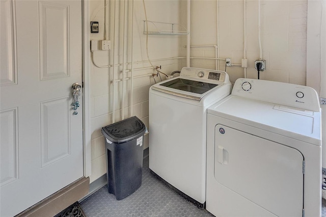 laundry room featuring tile patterned floors, laundry area, washing machine and dryer, and concrete block wall