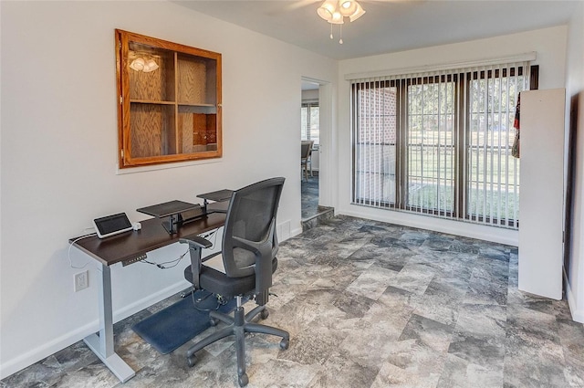 office space with stone finish floor, a ceiling fan, and baseboards