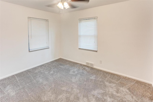 carpeted empty room with visible vents, baseboards, and ceiling fan