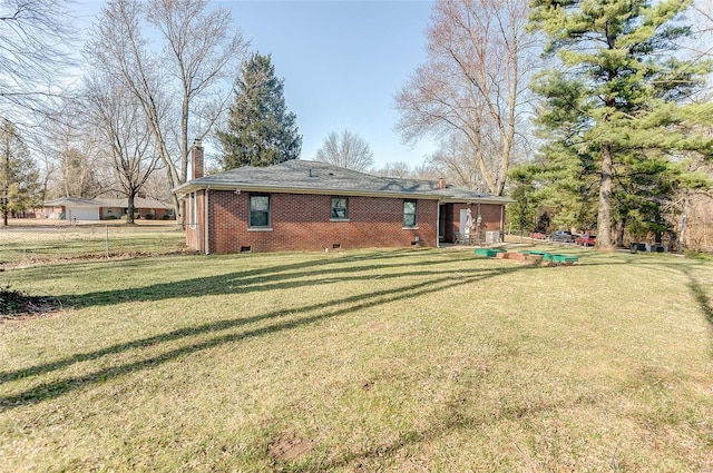 back of property with brick siding, crawl space, a yard, and a chimney