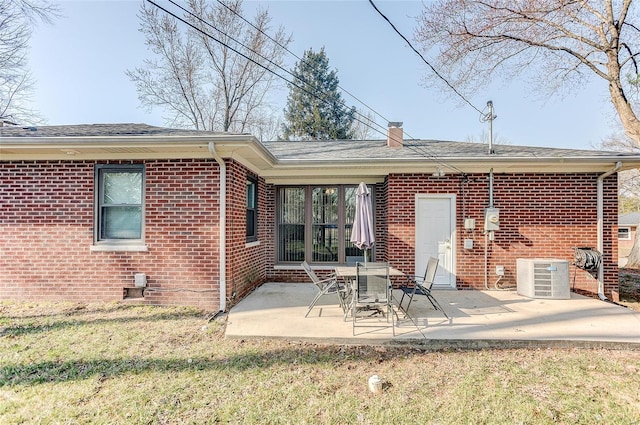 rear view of property with a patio area, a chimney, brick siding, and central AC