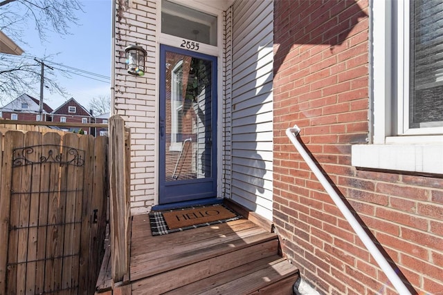 property entrance with brick siding and fence