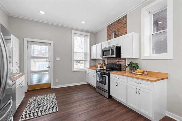 kitchen with dark wood-type flooring, appliances with stainless steel finishes, butcher block counters, and white cabinetry