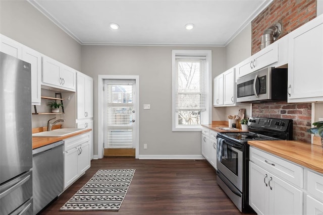 kitchen with baseboards, open shelves, dark wood-style flooring, a sink, and appliances with stainless steel finishes