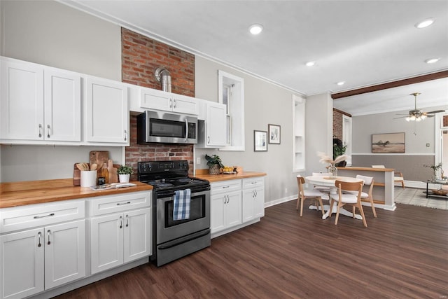 kitchen with white cabinetry, crown molding, appliances with stainless steel finishes, and butcher block counters