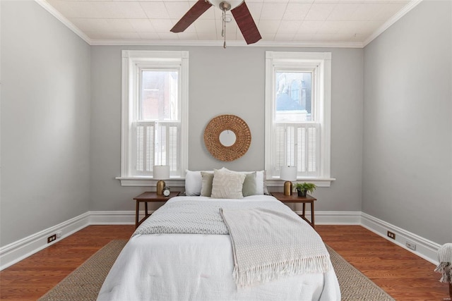 bedroom with multiple windows, wood finished floors, and baseboards