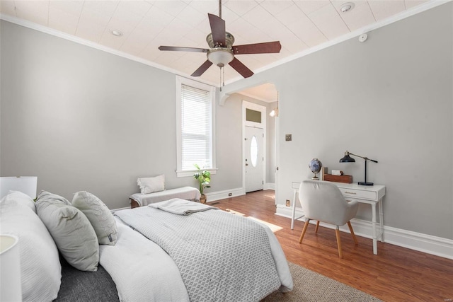 bedroom featuring crown molding, wood finished floors, arched walkways, and baseboards