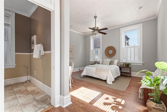 bedroom featuring a ceiling fan, crown molding, baseboards, and wood finished floors