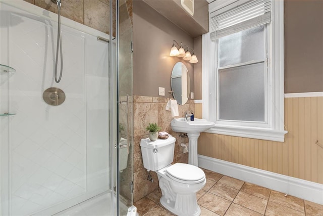 full bath featuring a shower stall, toilet, tile patterned floors, and wainscoting