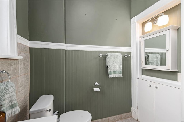 half bath featuring toilet and wainscoting