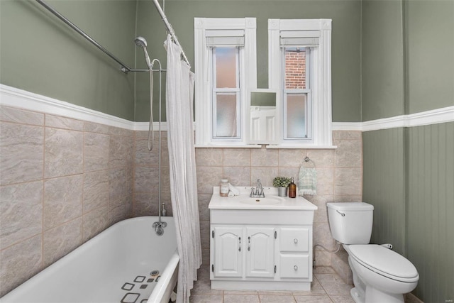 full bath featuring shower / bath combination with curtain, vanity, toilet, and tile walls