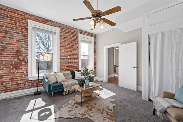 carpeted living area with baseboards and brick wall