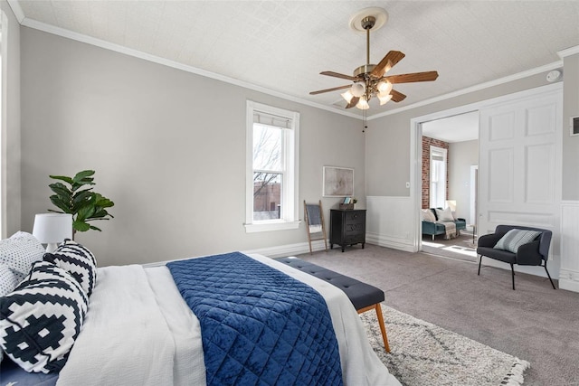 bedroom featuring carpet flooring, crown molding, and a wainscoted wall