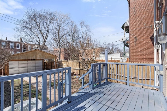 wooden deck featuring an outbuilding, a detached garage, and fence