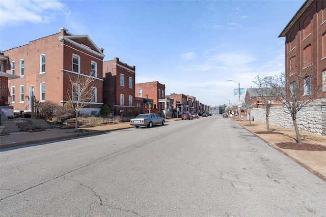 view of street with sidewalks, a residential view, curbs, and street lights