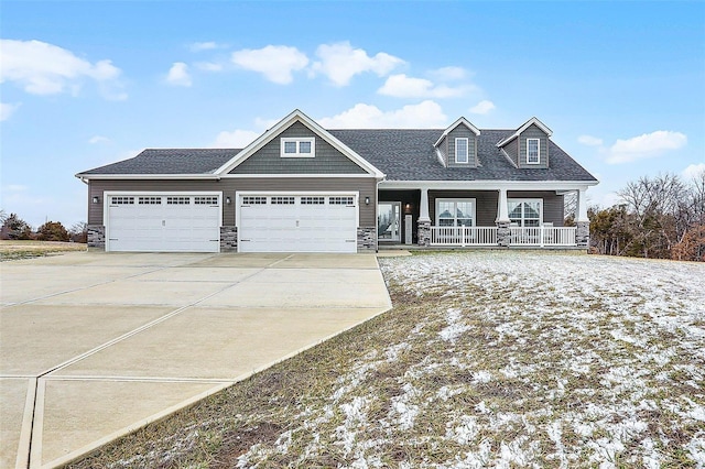 view of front facade featuring stone siding, a garage, covered porch, and driveway