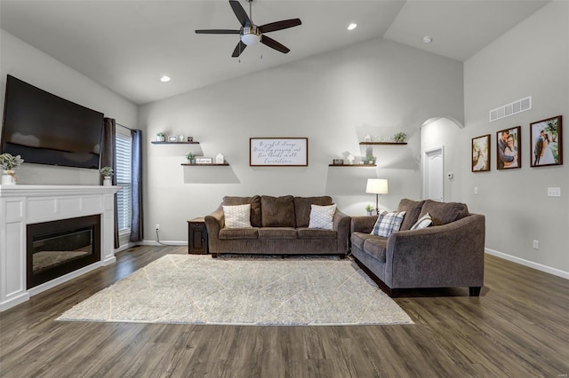 living room featuring visible vents, baseboards, dark wood-type flooring, and a glass covered fireplace