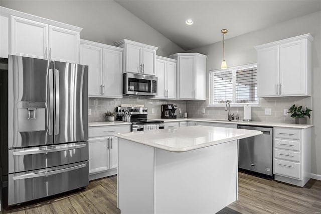 kitchen with dark wood-type flooring, vaulted ceiling, stainless steel appliances, white cabinetry, and a sink