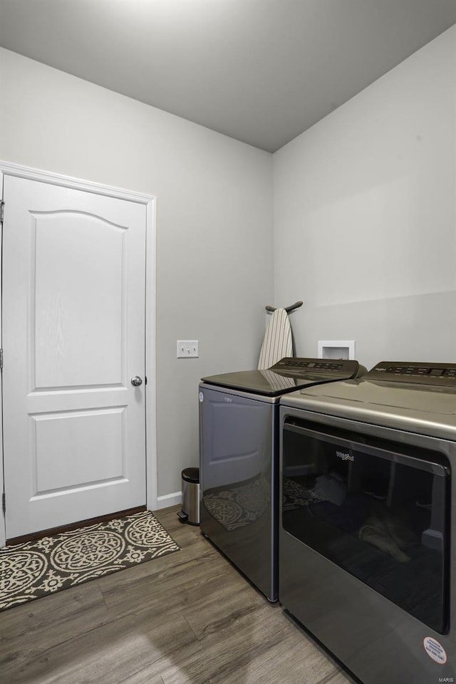 laundry room with washing machine and clothes dryer, laundry area, baseboards, and wood finished floors