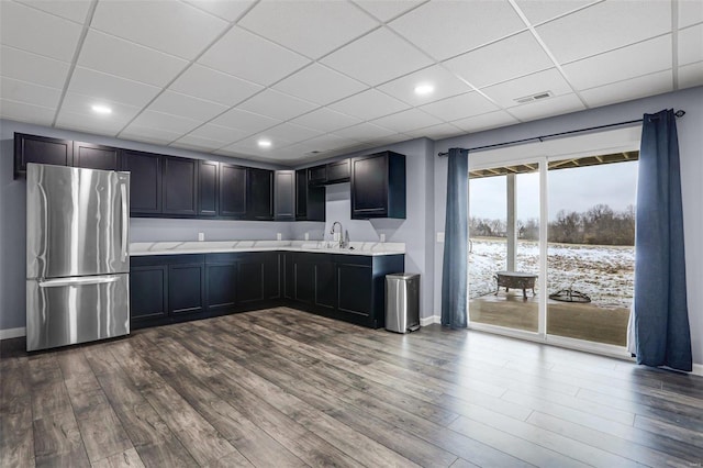 kitchen with visible vents, a drop ceiling, freestanding refrigerator, light countertops, and dark wood-type flooring