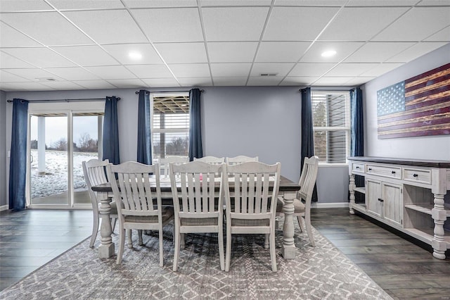 dining space featuring dark wood-style floors, visible vents, baseboards, and a drop ceiling