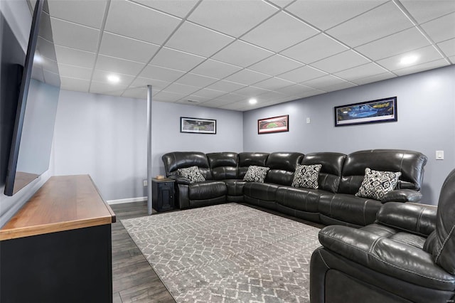 living room with dark wood-type flooring, a paneled ceiling, and baseboards