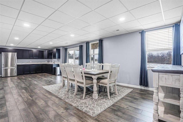 dining area with dark wood-type flooring, recessed lighting, a paneled ceiling, and baseboards