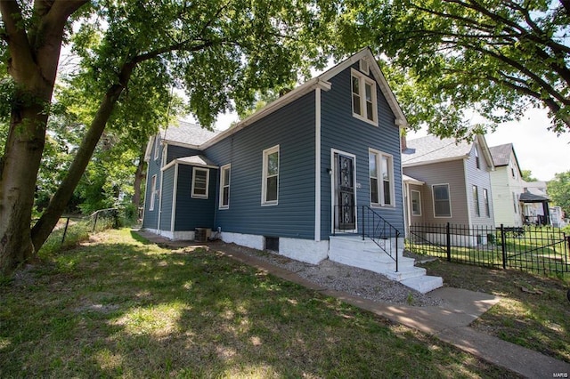 view of front of home featuring central AC, a front yard, and fence