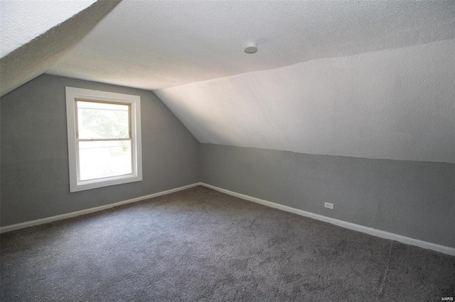 bonus room with lofted ceiling, baseboards, and a textured ceiling