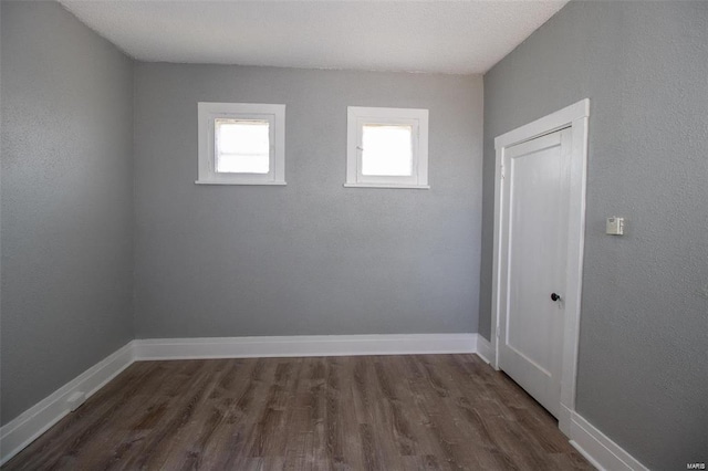 spare room with baseboards and dark wood-style floors