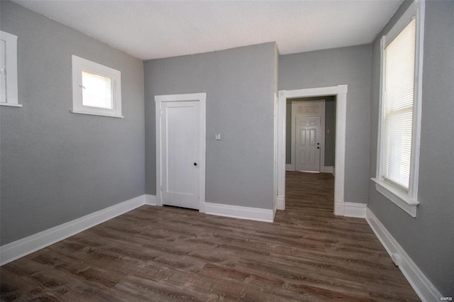 unfurnished room featuring baseboards and dark wood-type flooring