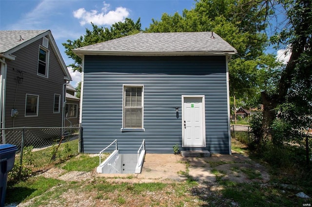 back of property featuring a shingled roof and fence