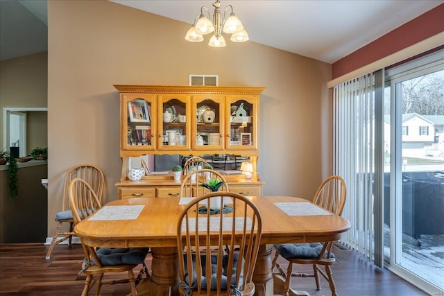 dining space featuring an inviting chandelier, dark wood-type flooring, visible vents, and vaulted ceiling