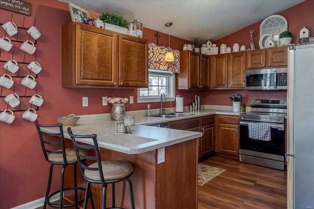 kitchen featuring a sink, appliances with stainless steel finishes, a peninsula, brown cabinetry, and light countertops