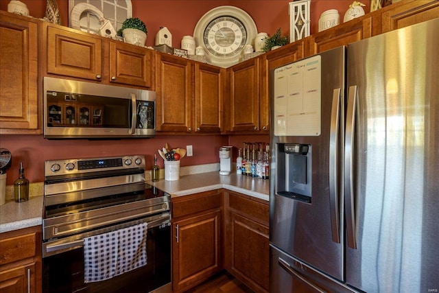 kitchen featuring brown cabinets, appliances with stainless steel finishes, and light countertops