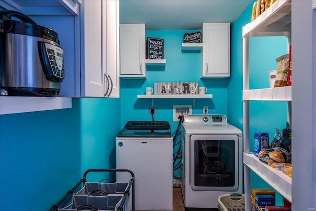 clothes washing area with washer and clothes dryer and cabinet space