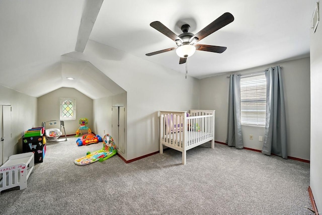 bedroom with a crib, a ceiling fan, vaulted ceiling, and carpet